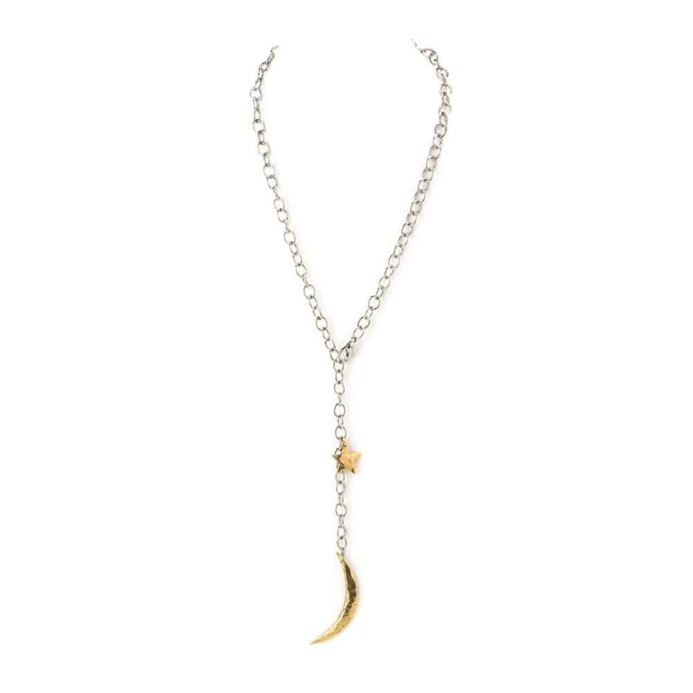 A solid link sterling silver chain necklace with a brass moon and star charm.
