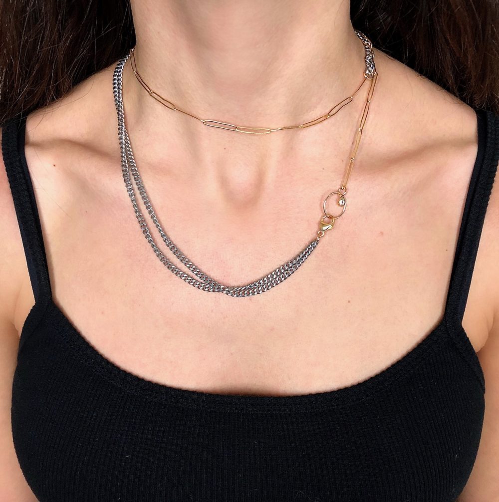 Close up on a woman's torso wearing a necklace with an oxidized sterling silver flat chain and 14k gold-filled paperclip chain.