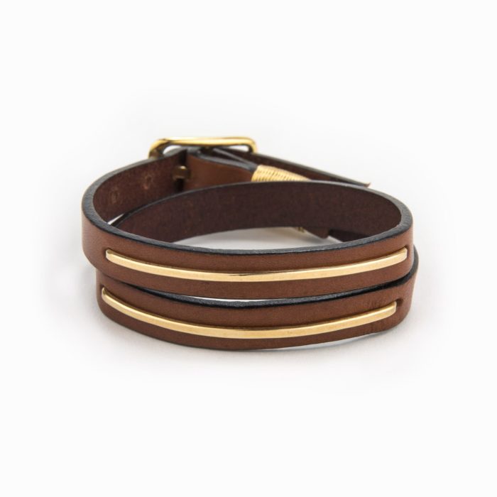 An adjustable 14k gold filled metal inlaid bracelet in brown leather with buckle closure.