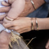 A close up on a father, mother and baby's arms together all wearing the custom stamped bracelets.