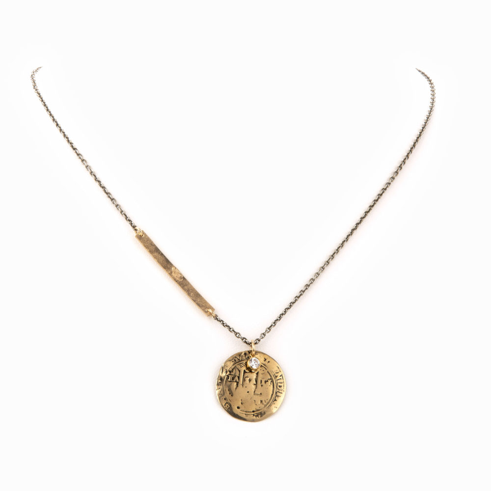 A delicate necklace with oxidized sterling silver chain, mixed with a rich, gold bar and a quarter-size antique coin.