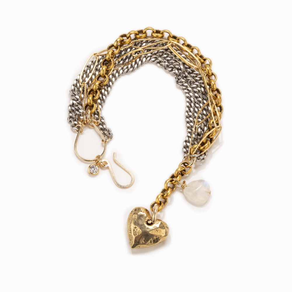 An adjustable bracelet of mixed silver and gold chains with brass heart charm, moonstone, small crystal details and easy-to-use clasp.