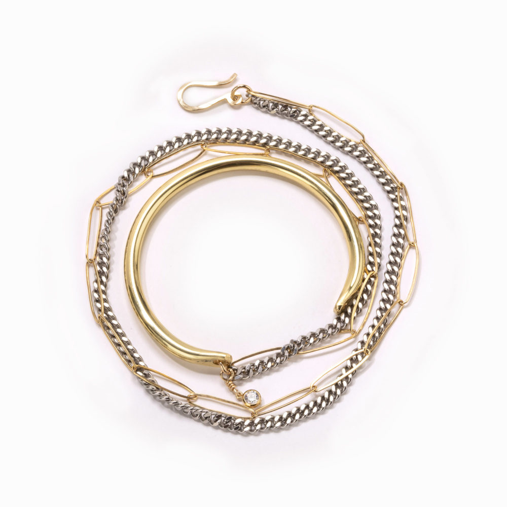 A wire wrap bracelet brass cuff, double wrapped beaded chains in gold and silver, and lobster claw closure.