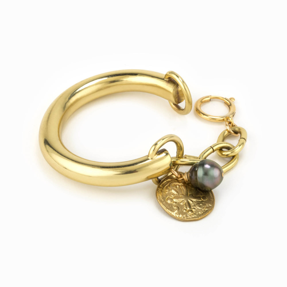 Rear view of a chunky brass bracelet with stamped coin charm and tahitian pearl.