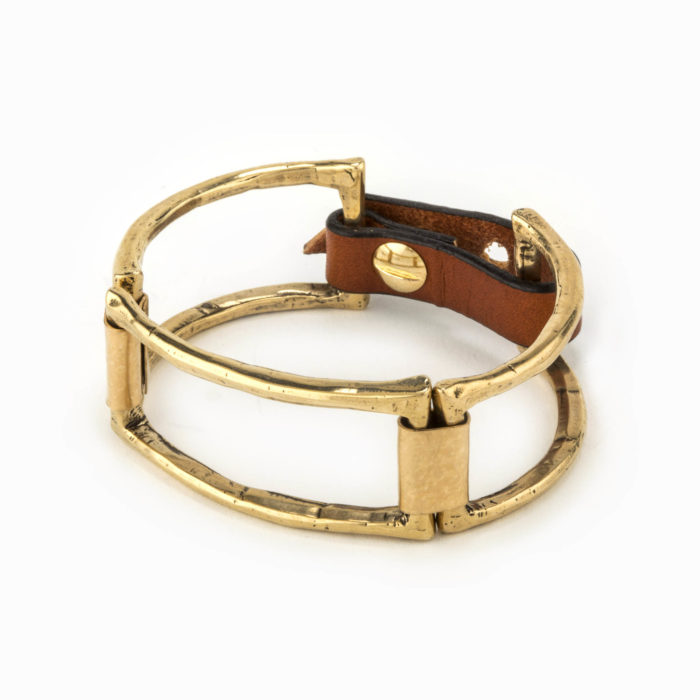A brass cuff with large square pieces linked together with 14k gold fill plates and an adjustable leather closure.