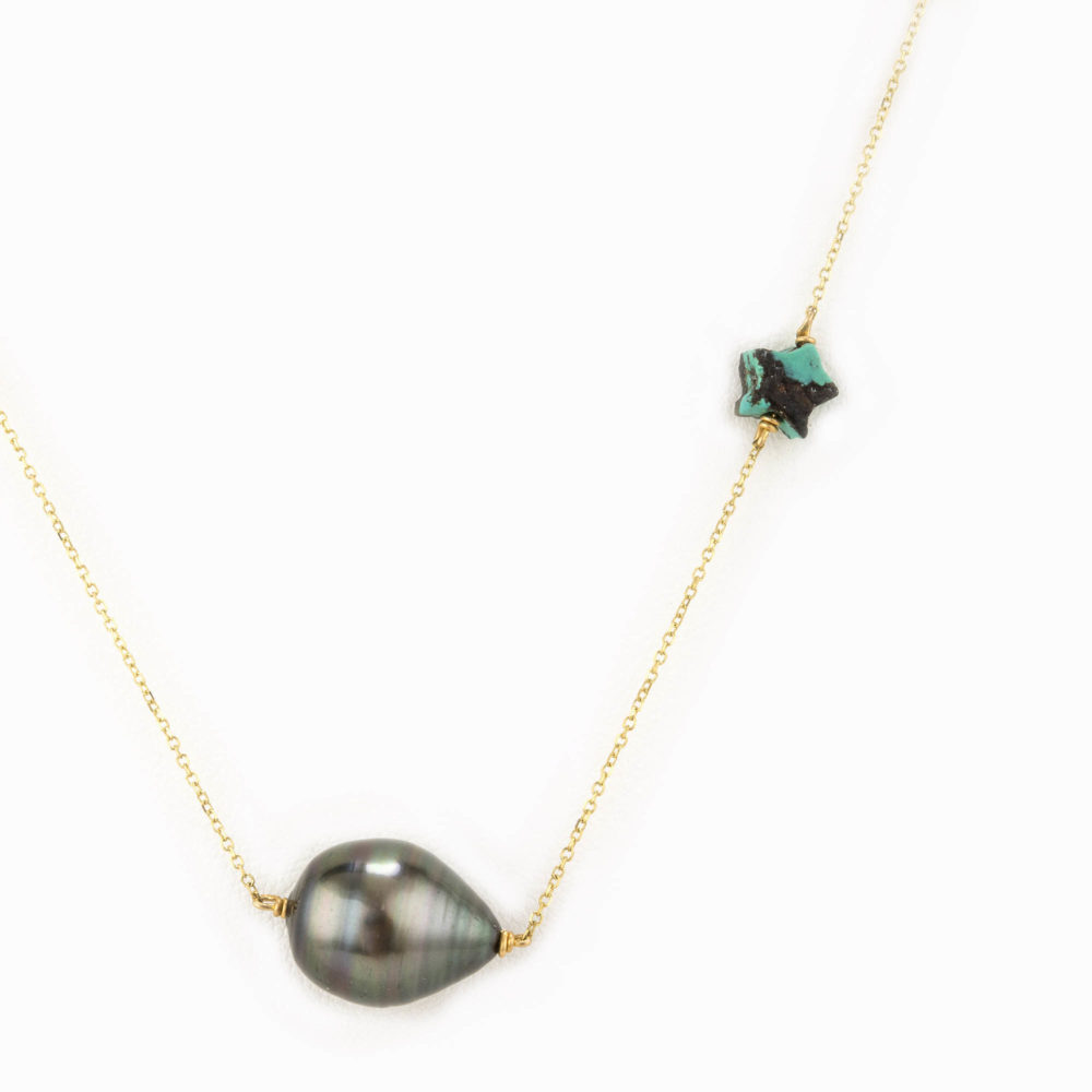 Close up on a turquoise star and black pearl on a gold chain.