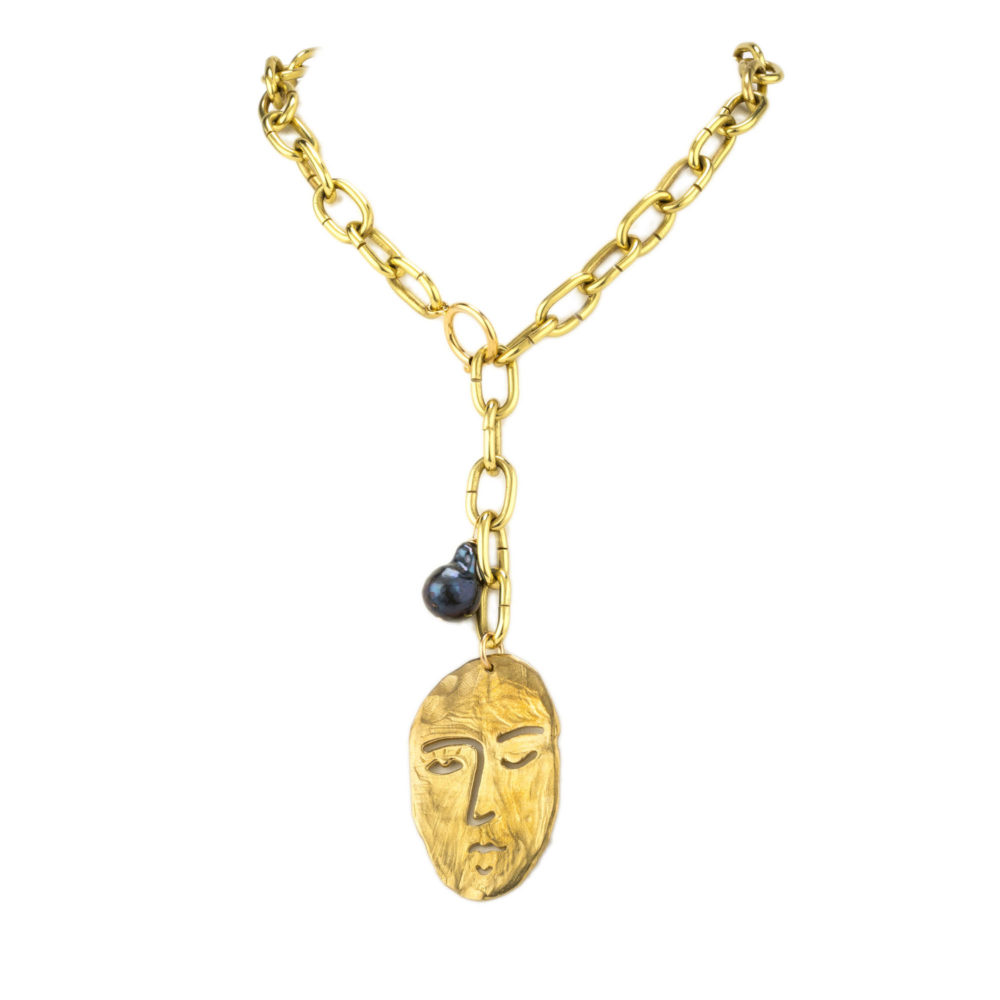 A necklace with a thick brass chain, hand-casted brass face charm, and tahitian pearl.