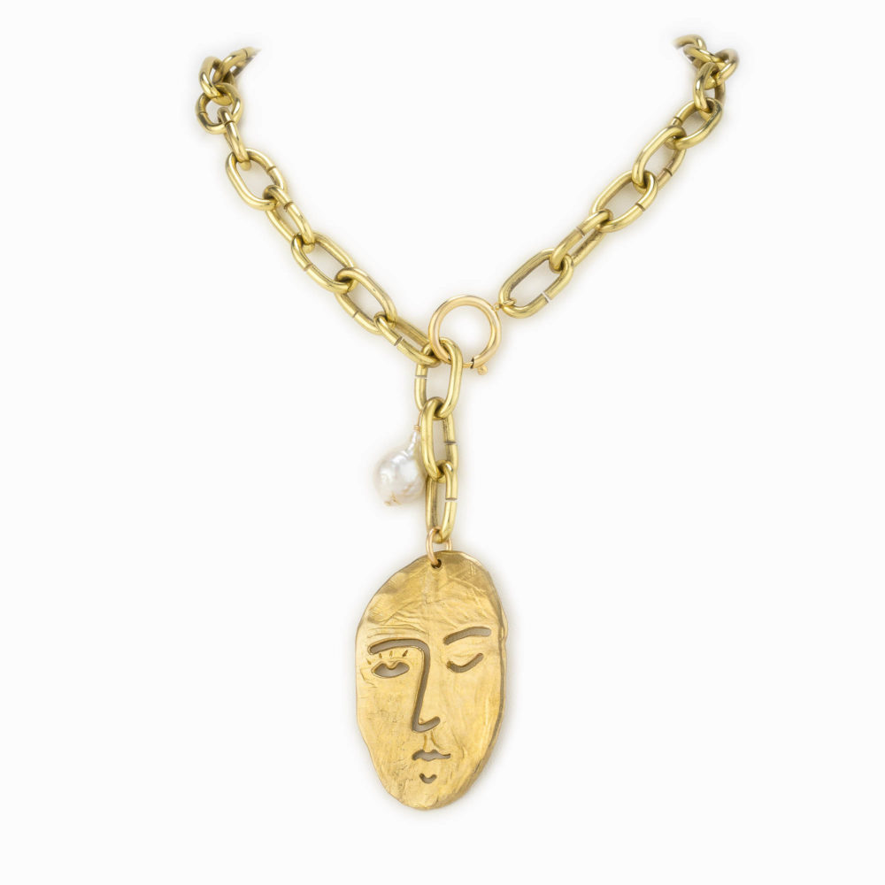 Brass chain necklace with a large carved face charm and baroque pearl.
