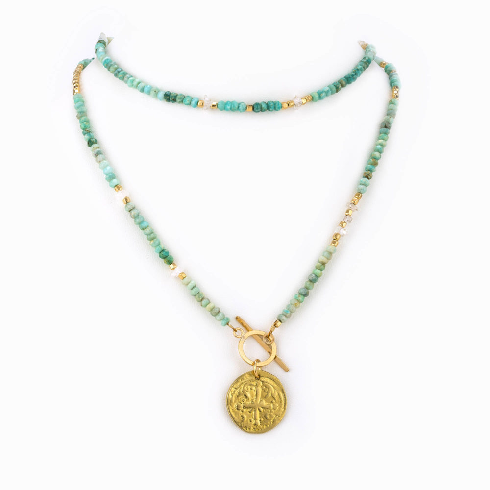 A multicolored amazonite necklace with Herkimer quartz and gold beads with a brass antique coin charm.