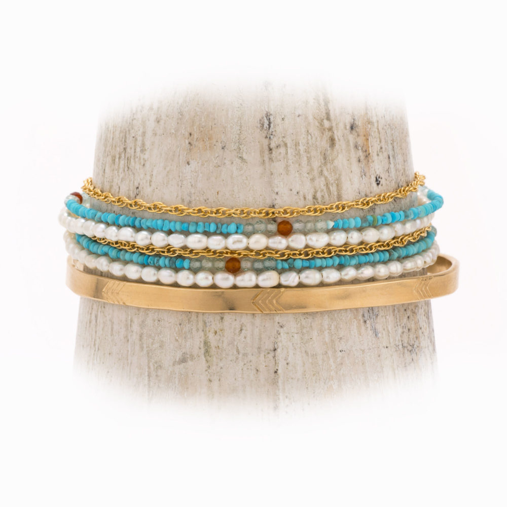 A 14k gold-filled wire bracelet double wrapped with strands of pearl, turquoise, carnelian and gold chain, with a lobster claw closure.