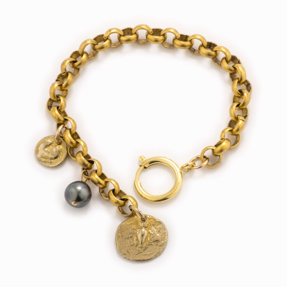 An adjustable brass rolo chain bracelet with a stamped coin charm and tahitian pearl.