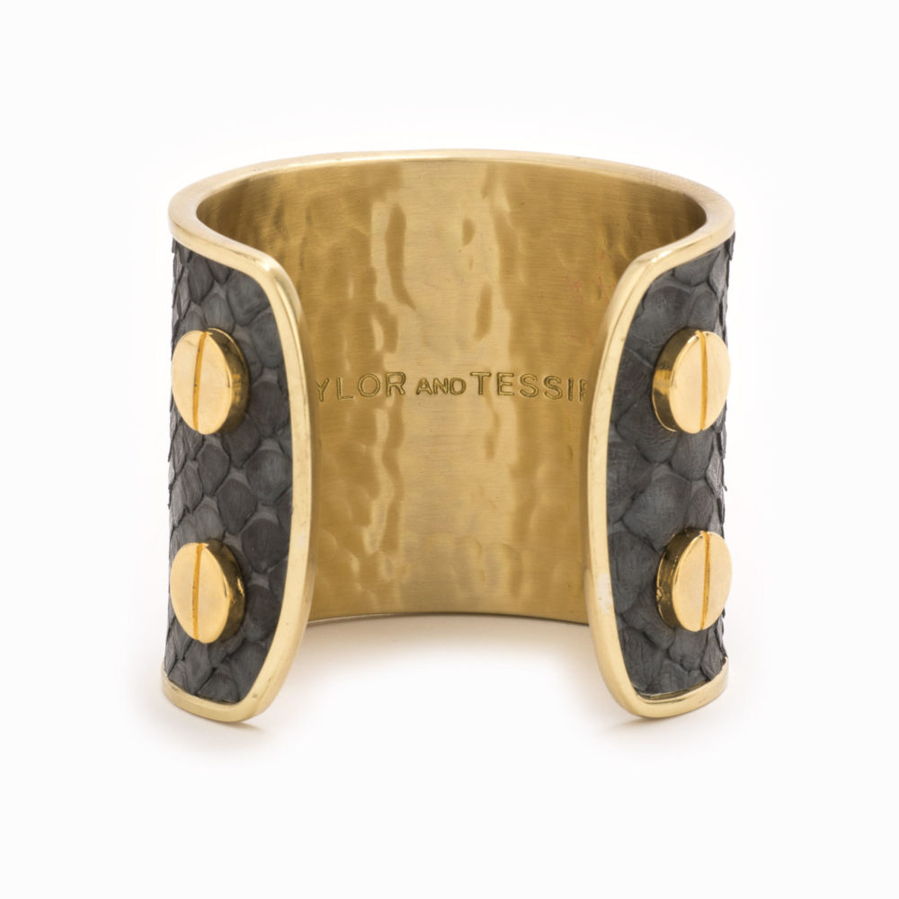 Rear view of a large gold cuff with charcoal colored snakeskin pattern inlaid.