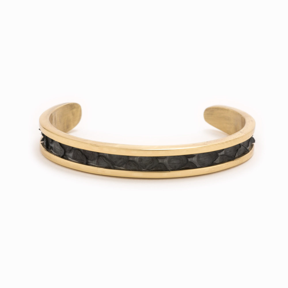 A small gold cuff with charcoal colored snakeskin pattern inlaid.