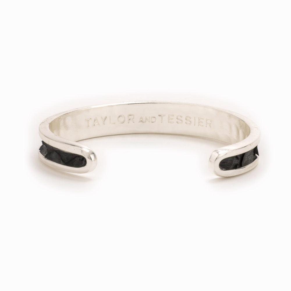Rear view of a small silver cuff with charcoal colored snakeskin pattern inlaid.
