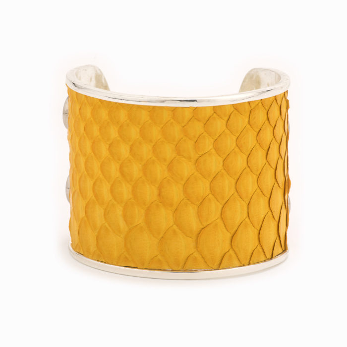 A large silver cuff with mustard colored snakskin pattern inlaid.