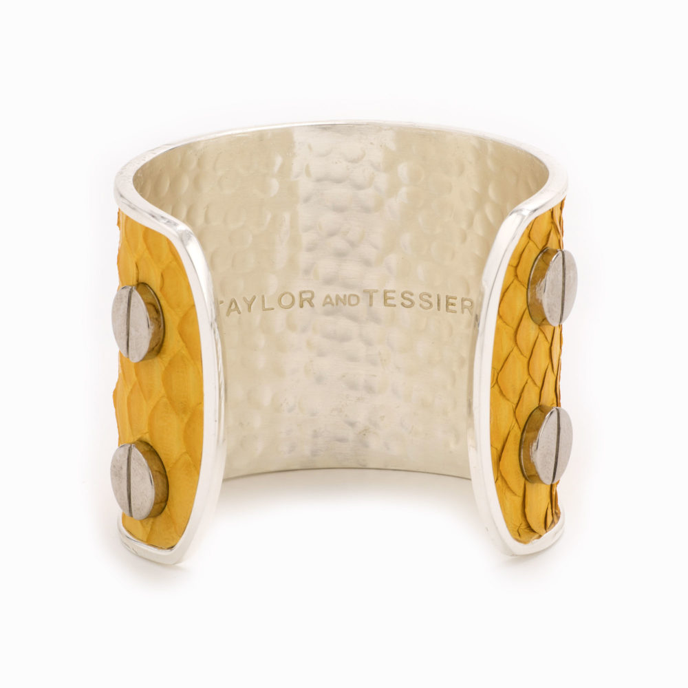 A large silver cuff with mustard colored snakskin pattern inlaid.