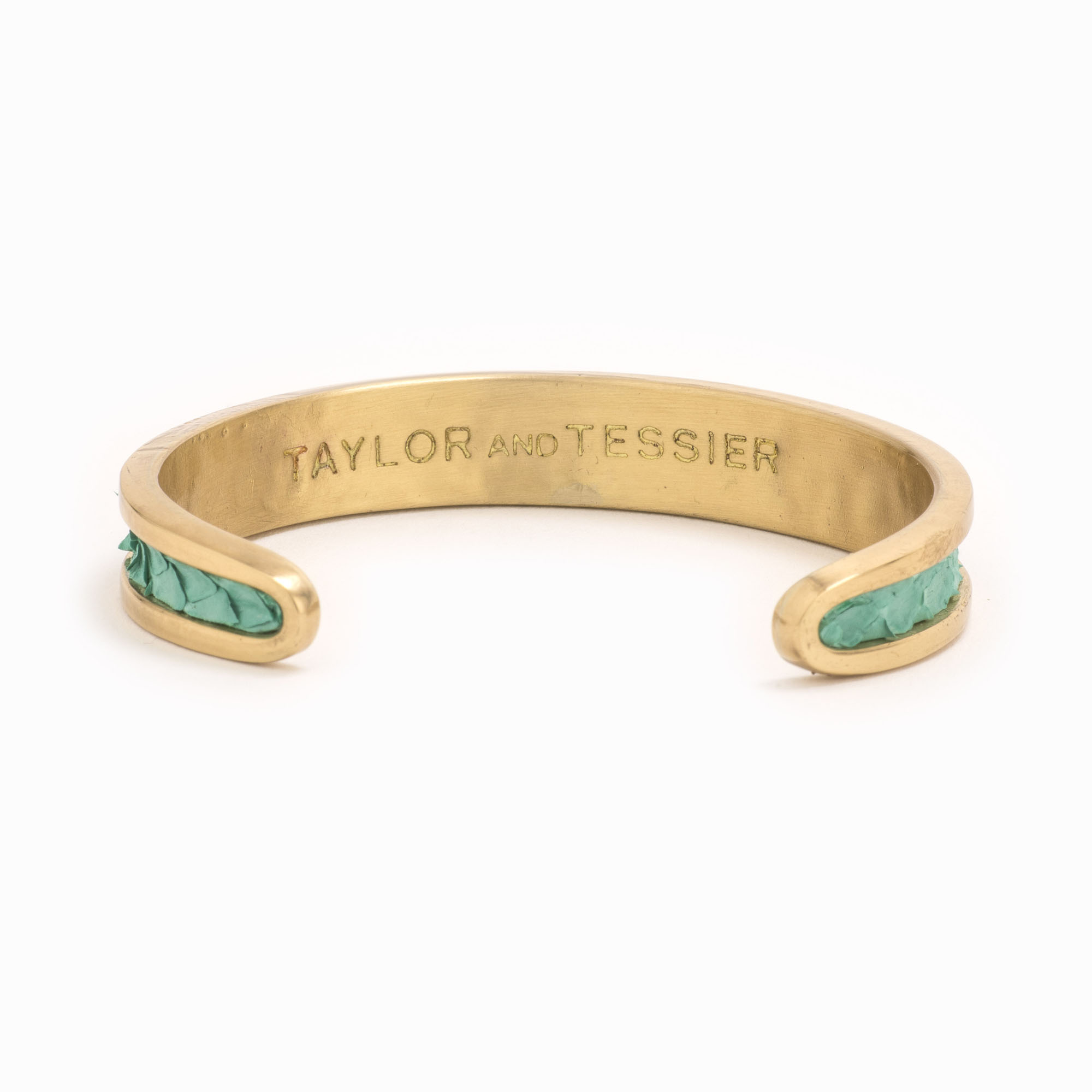 A small gold cuff with turquoise colored snakeskin pattern inlaid.