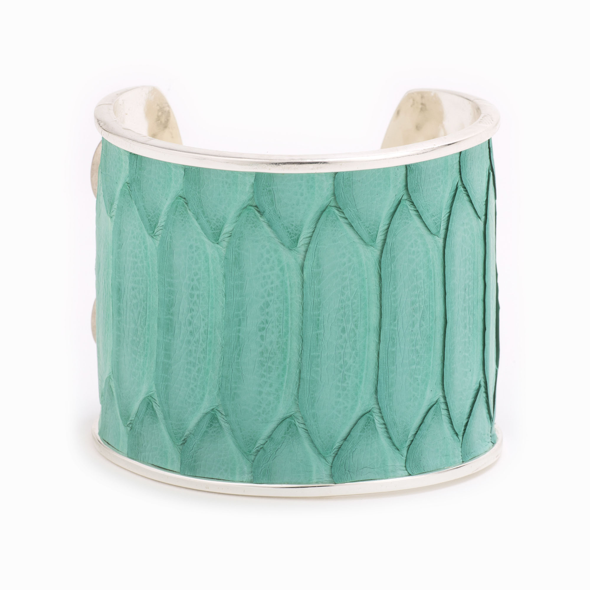 A large silver cuff with turquoise colored snakeskin pattern inlaid.
