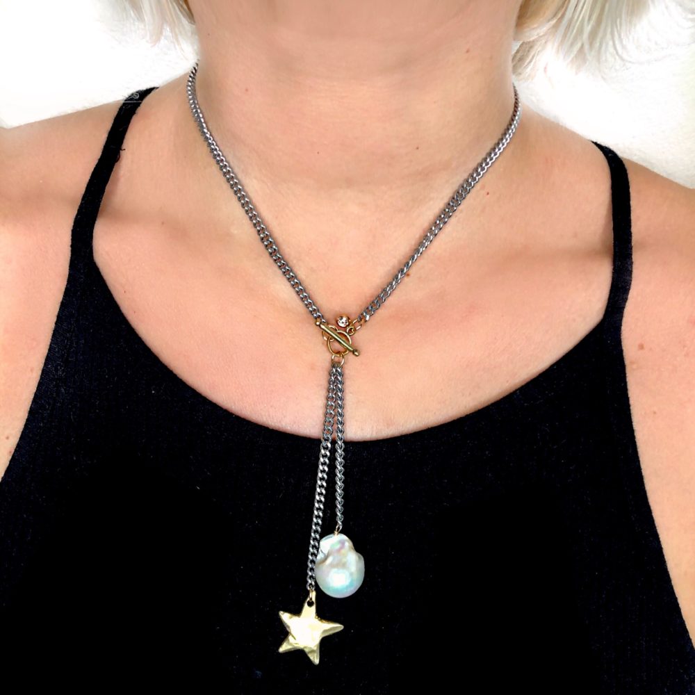 A flat silver short chain necklace with gold star and white baroque pearl drop.
