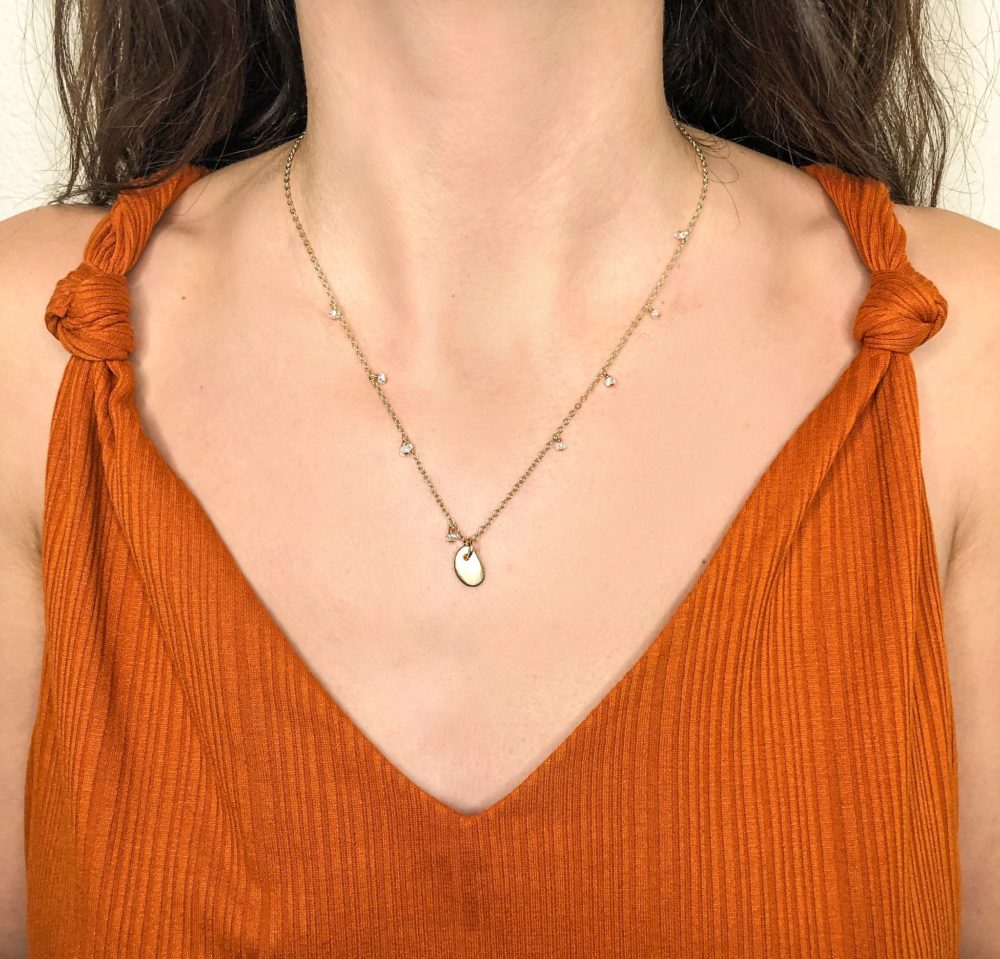 Close up on a woman's neck wearing a14k gold-filled chain necklace with a brass pebble and Herkimer quartz pieces.