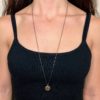 Close up on a woman's torso wearing a long gold vermeil beaded necklace with oxidized silver chain and completed with brass charms.