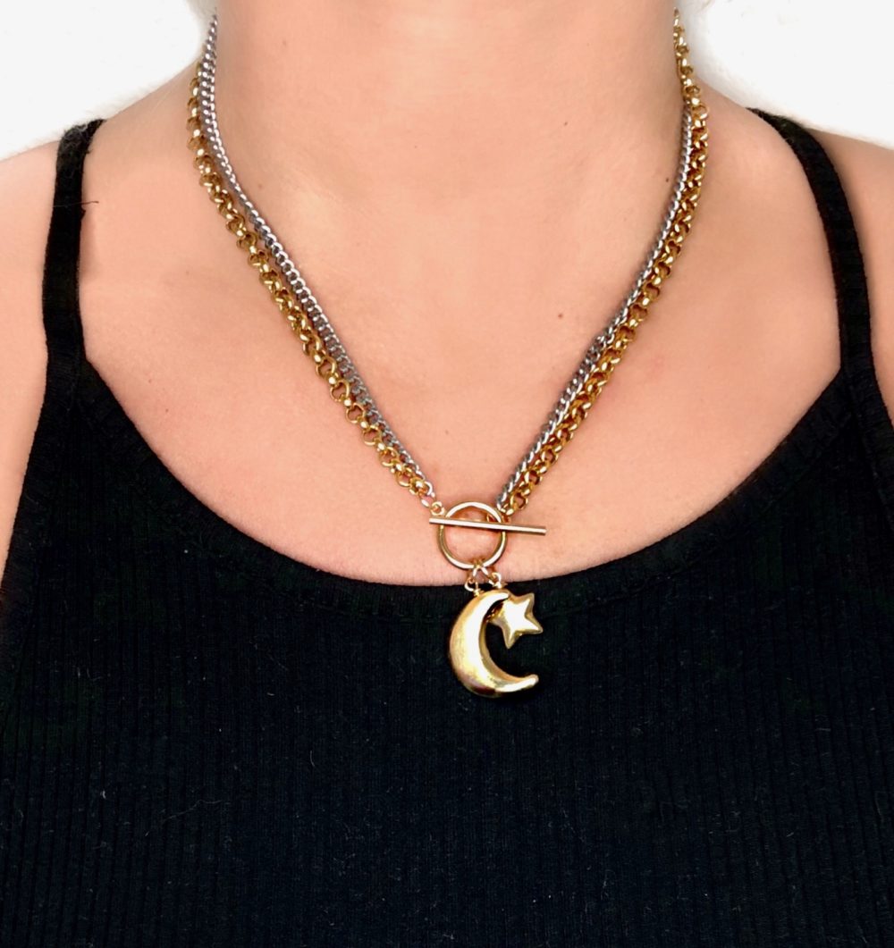 Close up on a woman's torso wearing a flat oxidized sterling silver chain and brass rolo chain necklace with a 14k gold-filled front closure and brass star and moon charms.
