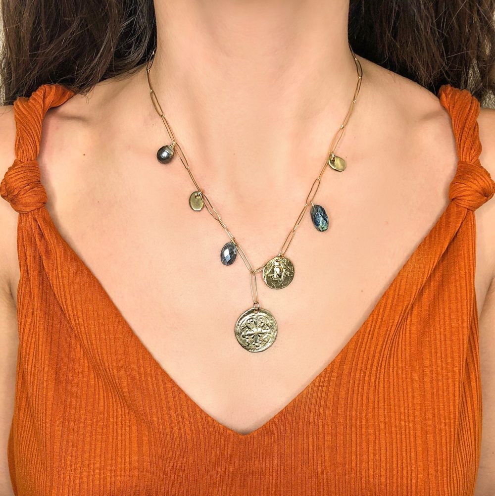 Close up of a woman's neck wearing a 14k gold-filled paperclip chain with brass coins, pearlized agate and pearl charms.