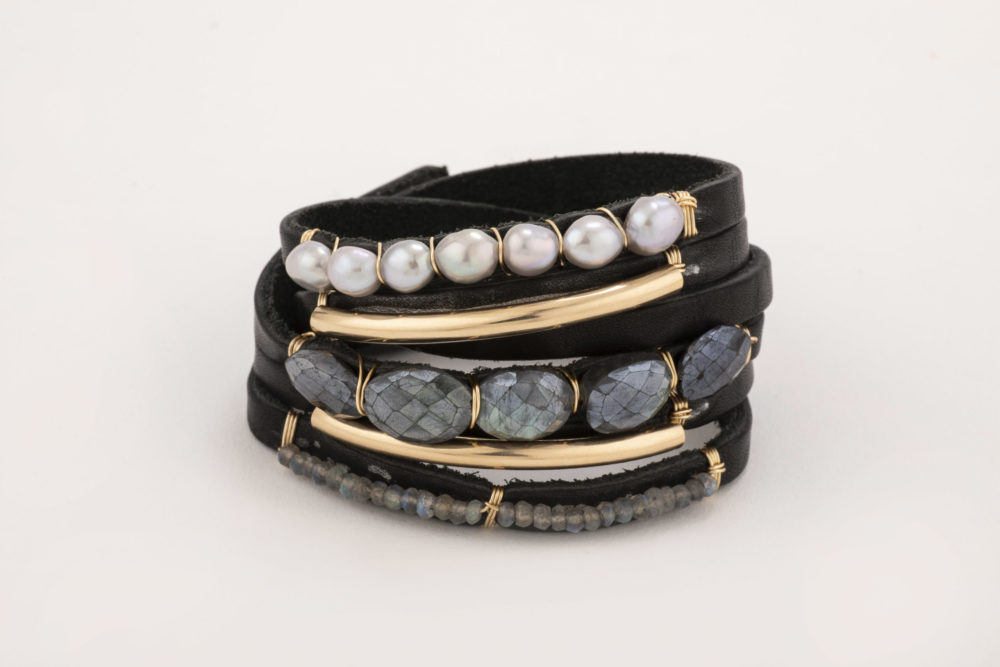 Front view of a black leather shred bracelet featuring labradorite beads and pearls and finished with a 14k gold bar against a plain white background.